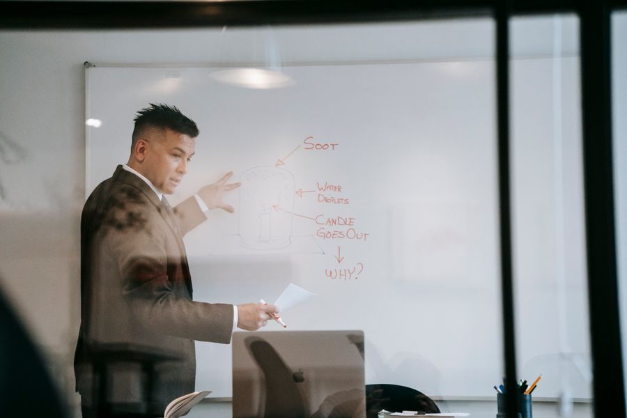 Business coach mapping out a plan on a whiteboard during a one-on-one coaching session