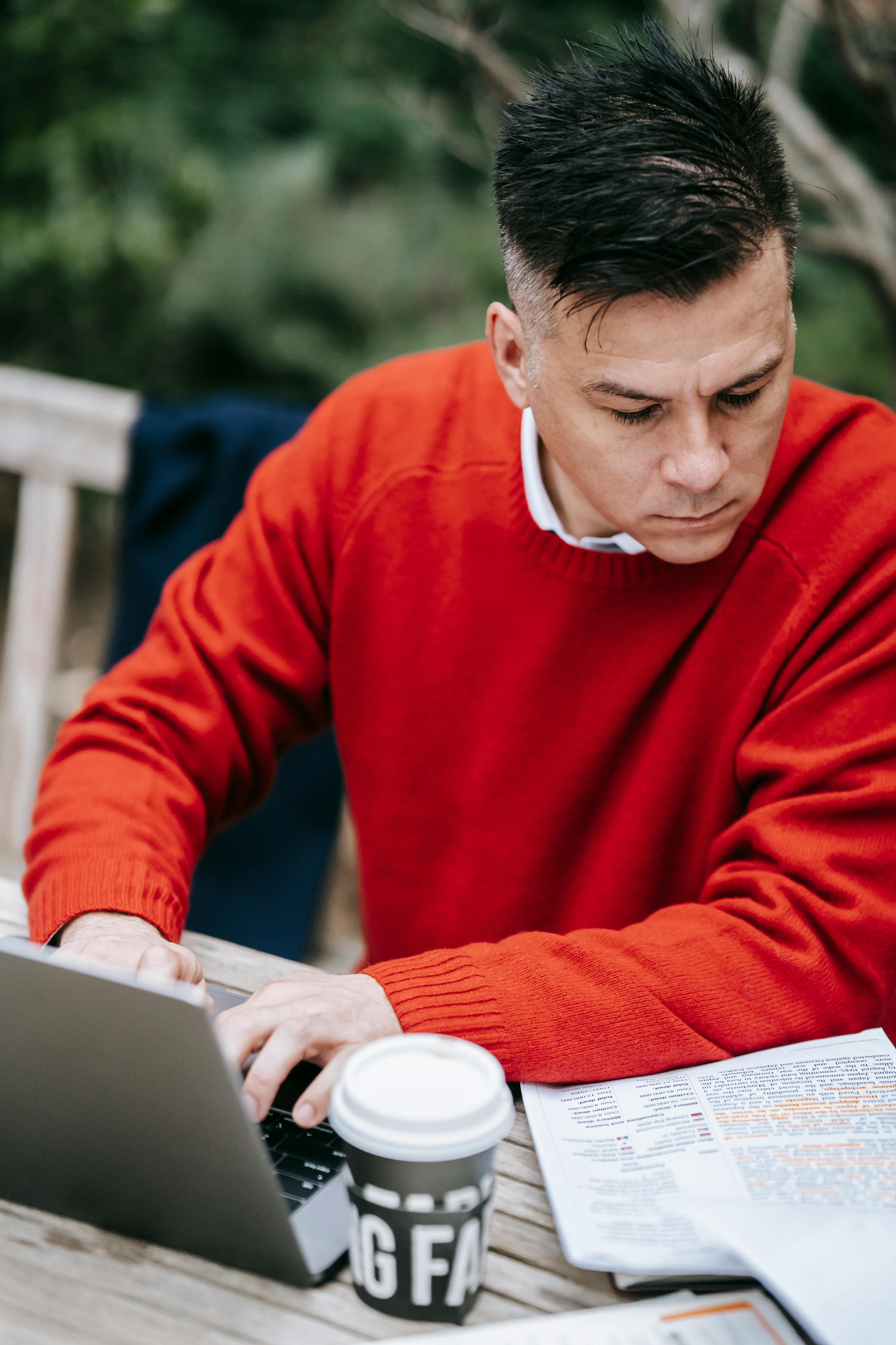 man in red sweater using macbook