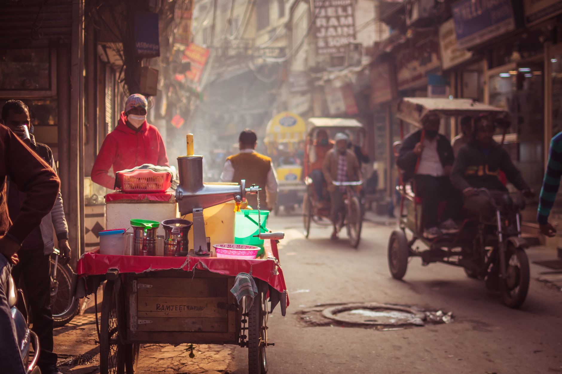 Street vendor in bustling New Delhi market selling food amidst vibrant, busy atmosphere.