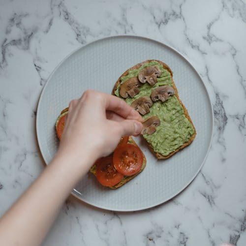 avokado tostları, domates, el içeren Ücretsiz stok fotoğraf