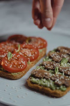 Close-up of healthy vegan avocado toast with fresh tomato, mushrooms, and sesame seeds.