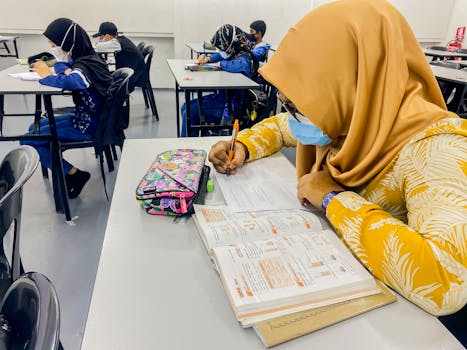 A group of students in Malaysia studying in a classroom, focused and wearing masks.