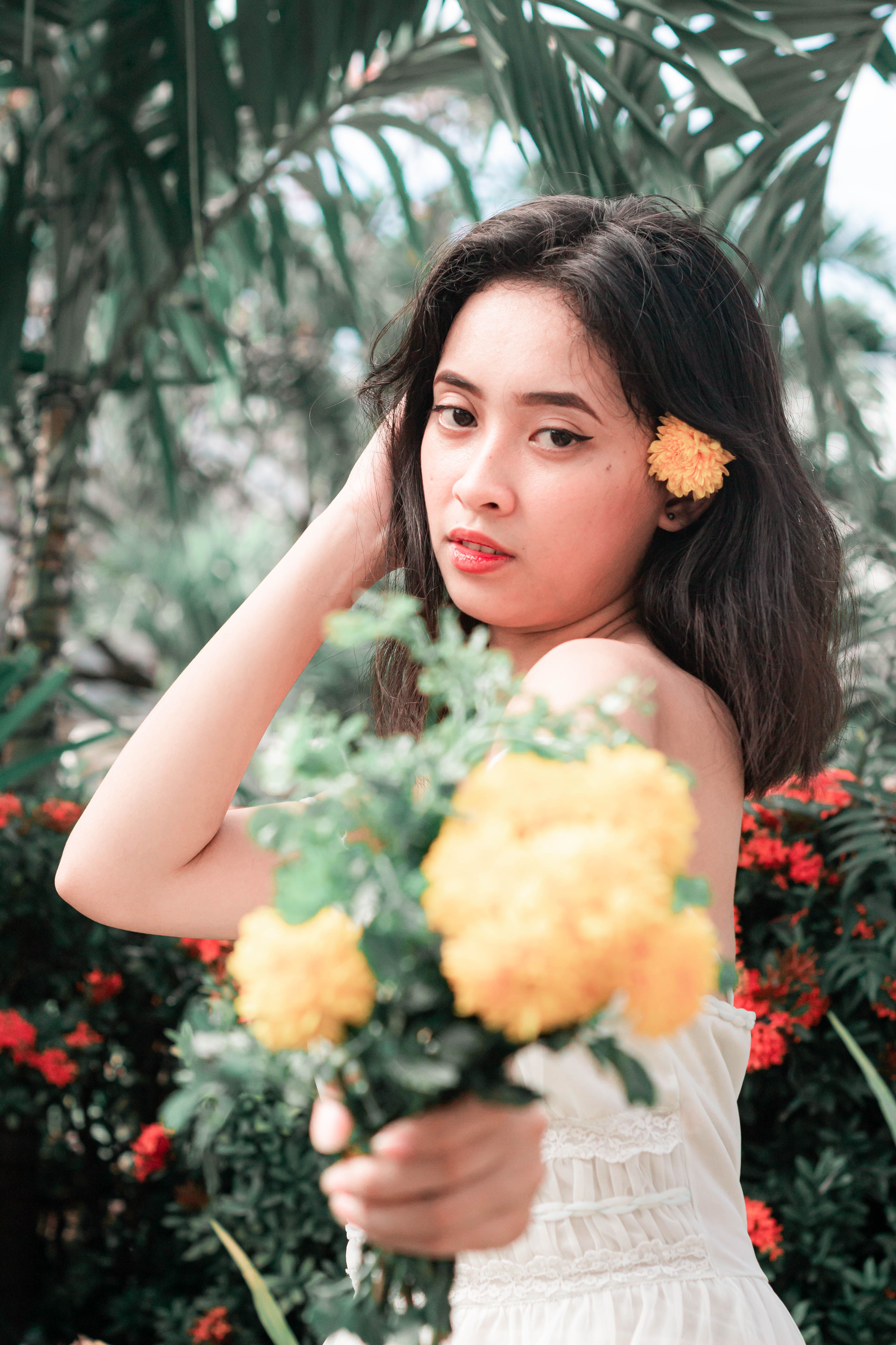 A Pretty Woman in White Dress Holding Flowers · Free Stock Photo