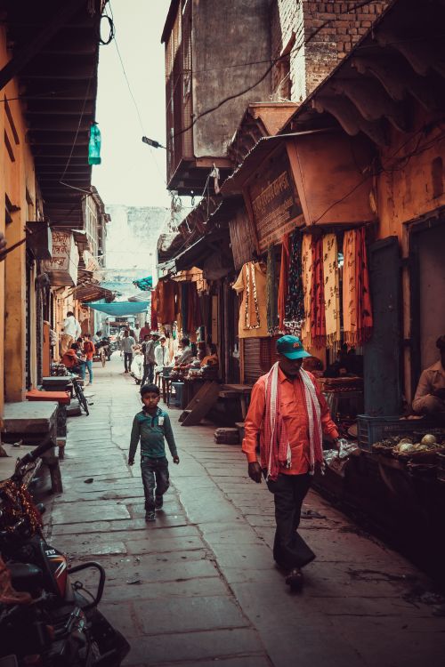 Free Vibrant scene of a bustling Indian alley with people and market stalls. Stock Photo