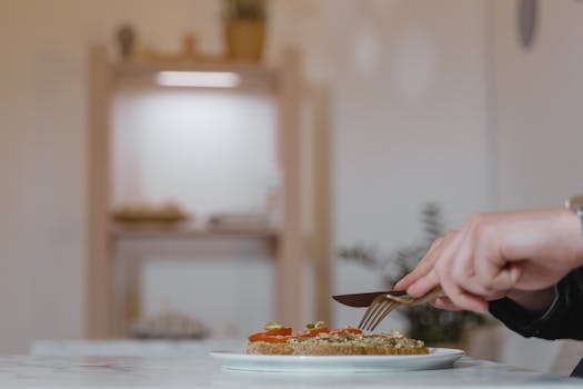 A hand slicing vegan sandwich on a ceramic plate with focus on healthy lifestyle.