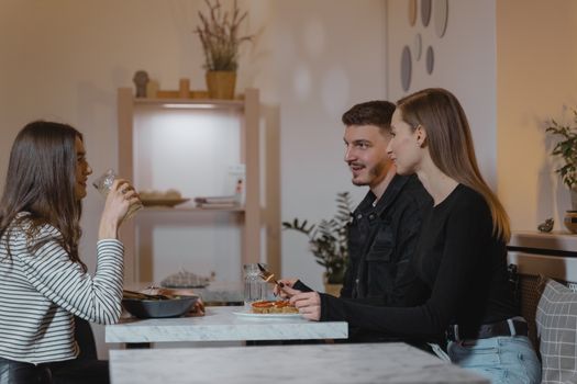 A group of three friends enjoying a meal at a stylish indoor setting, capturing a moment of conversation and camaraderie.