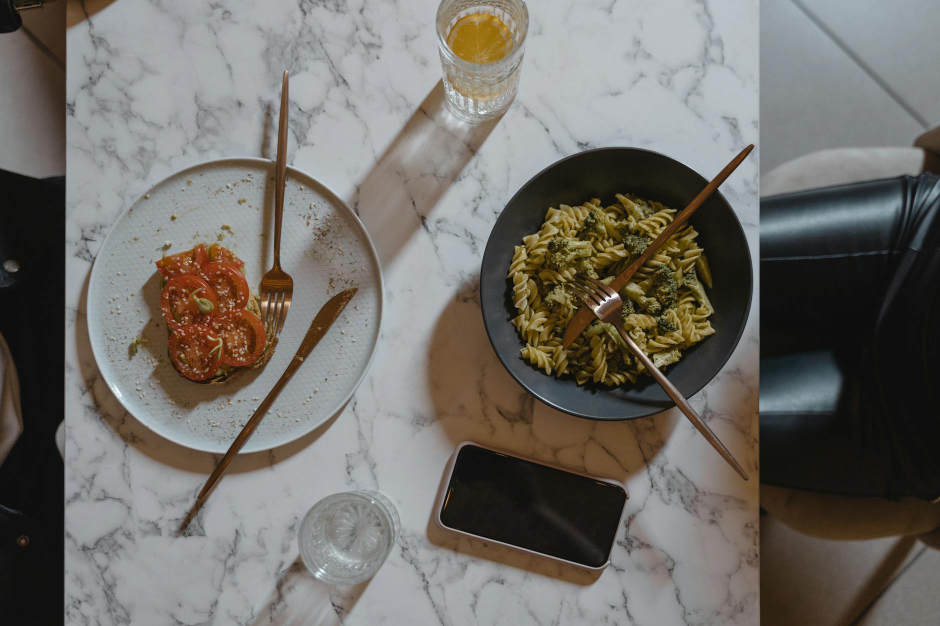 Pâtes Crémeuses Aux Légumes Et Pesto Léger : Recette Healthy &Amp; Facile 266 Overhead view of a vegan pasta and tomato salad meal on a marble table with a phone.