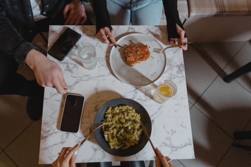 Free Overhead view of a casual meal with pasta and bruschetta on a marble table. Friends enjoy food together. Stock Photo