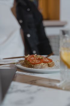 A close-up of fresh sliced tomato on bread, garnished and served on a ceramic plate.