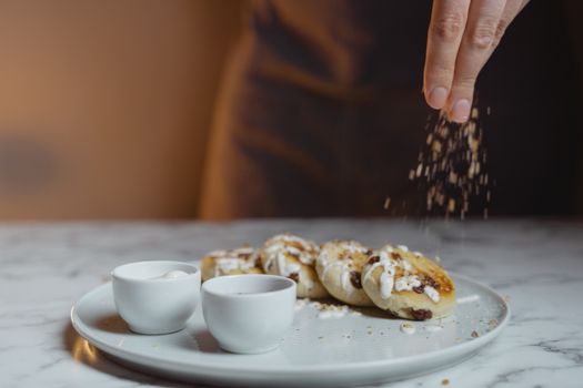 Candid food photography of welsh cakes being sprinkled with nuts, captured on a marble surface.