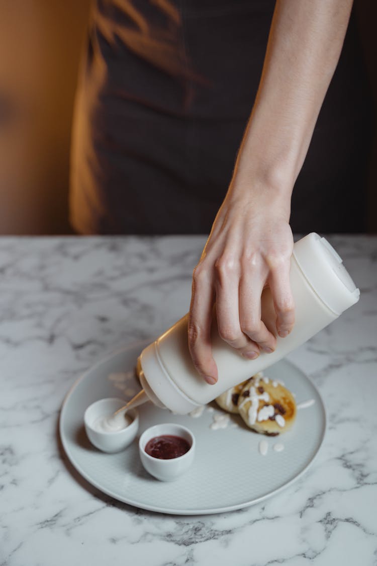 Person Putting White Sauce In Souffle Cup