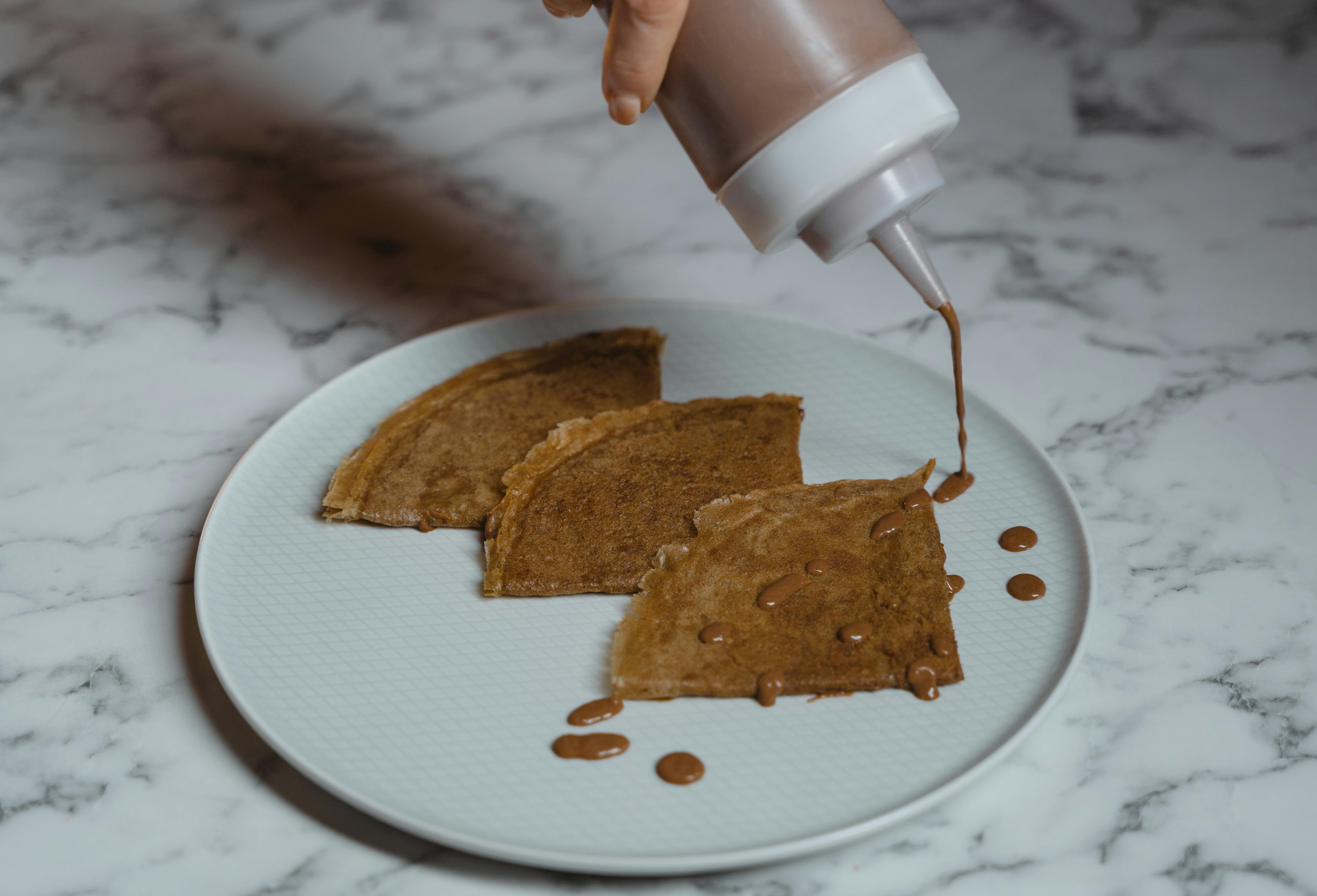 person pouring milk from a cup to a bread