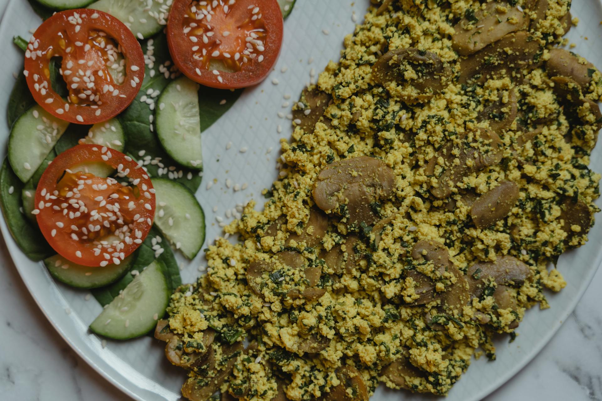 A Vegan Food with Sliced Tomatoes and Cucumbers on the Side