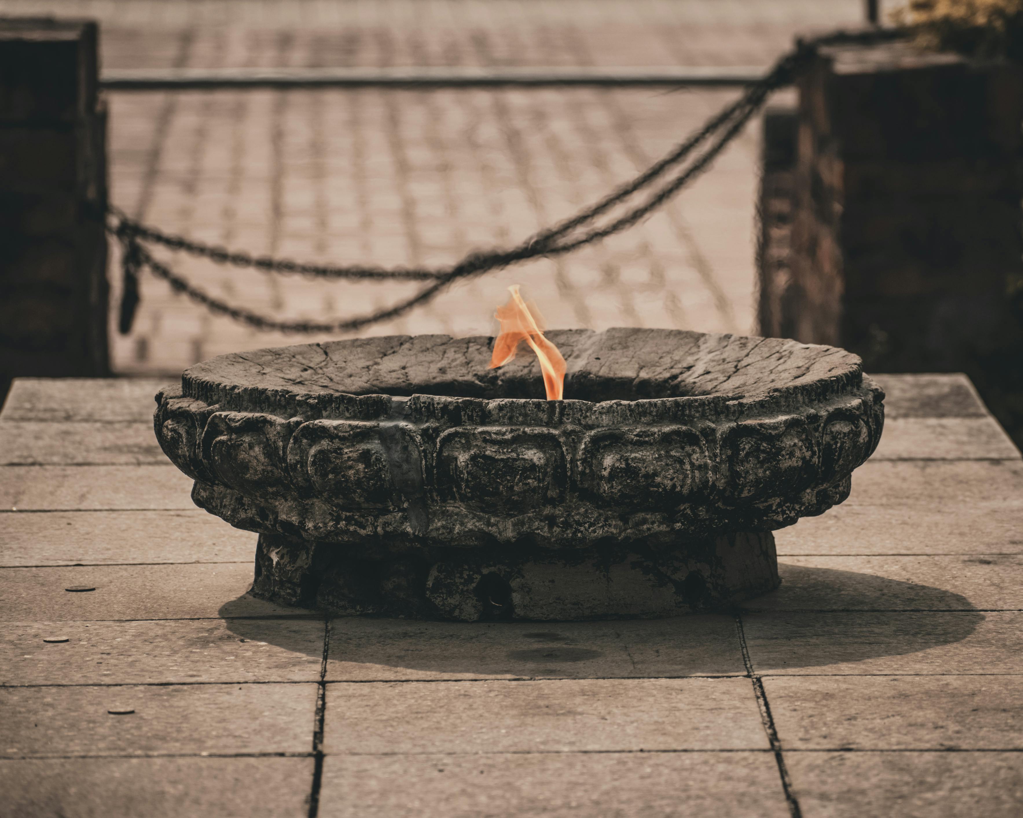 A sacred flame burns on a stone burner in Lumbini, capturing spiritual essence. - Lumbini