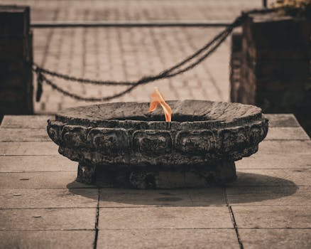 A sacred flame burns on a stone burner in Lumbini, capturing spiritual essence.