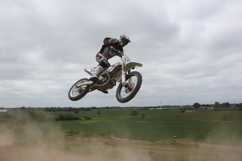 Man Riding Moto Cross Bike Macht Tricks In Der Luft Unter Bewölktem Himmel Während Des Tages