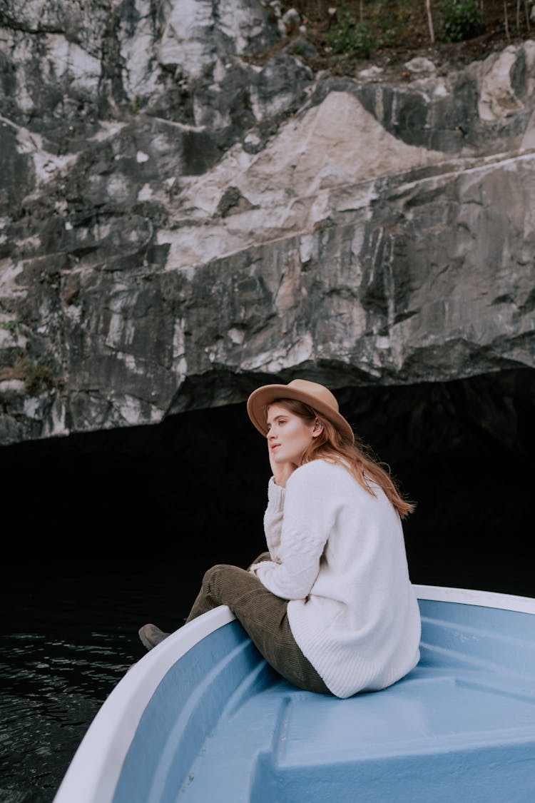 Woman In White Sweater And Brown Fedora Hat Sitting On Blue And White Boat