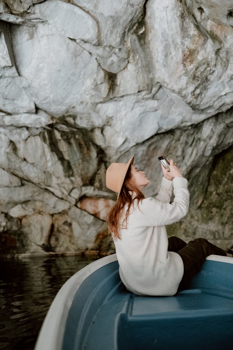 Woman In White Long Sleeve Shirt And Brown Fedora Hat Sitting On Boat Taking Picture