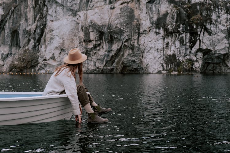 A Woman Sitting On The Boat While Looking At The Rock Formation