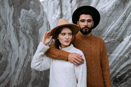 Man in Brown Knitted Sweater Hugging Woman in White Sweater