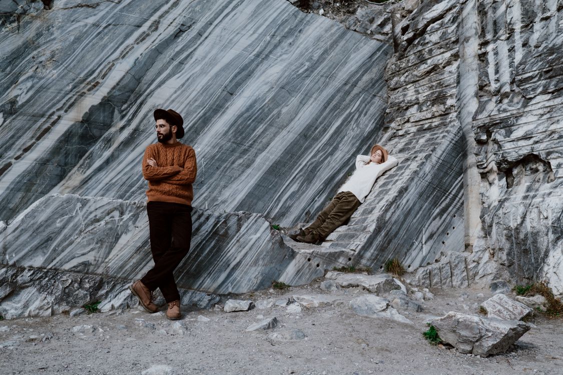 Man and Woman in Hats Standing and Lying Down on Rocks · Free Stock Photo