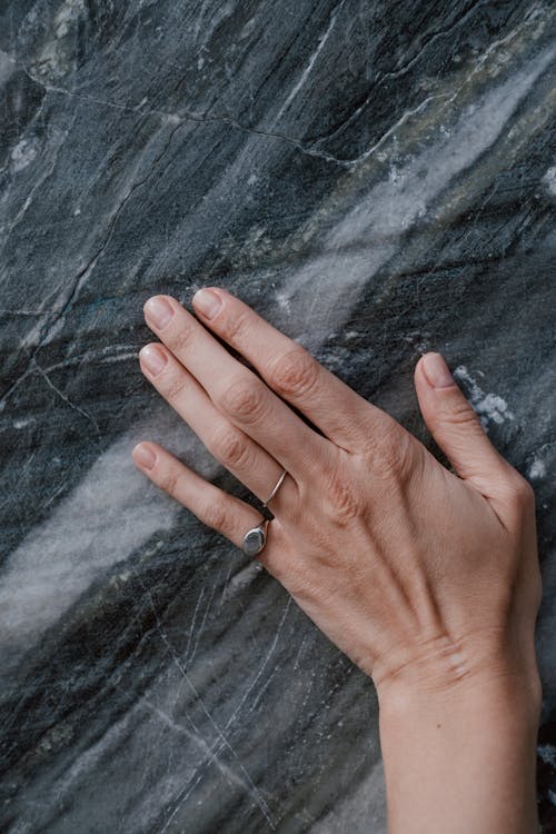 Hand of Person Wearing Rings on Rock