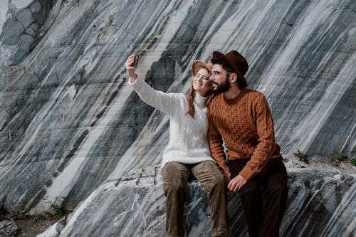 A Couple Sitting on Granite Rocks Taking a Selfie