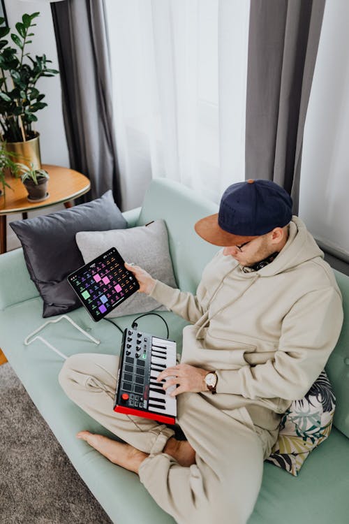 Man Sitting on a Couch Playing Akai Professional MPK Mini Play