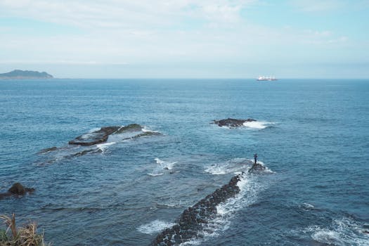 A breathtaking seascape featuring rocks, turquoise waters, and a ship on the horizon. Perfect for travel inspiration.