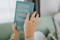 A Person with Finger Rings Holding a Green Book