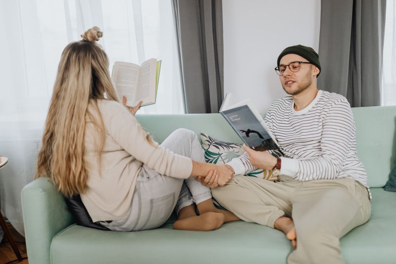 A couple enjoys a relaxing moment reading books together on a cozy sofa.