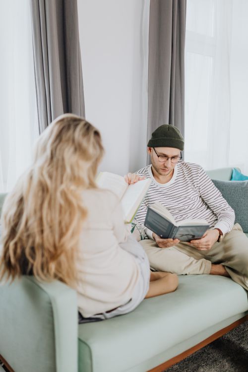 Free Cozy couple reading together on a sofa at home, enjoying relaxation and leisure time. Stock Photo