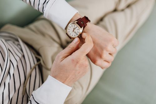 A person adjusting a leather-strapped field watch on the wrist, photo by Kaboompics on Pexels