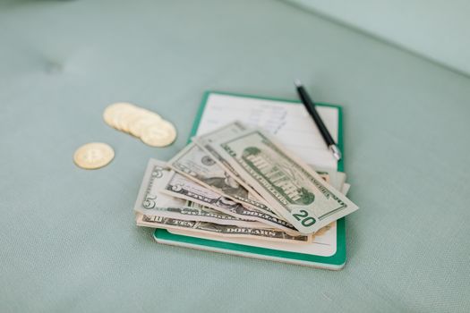 Close-up of American dollar bills and coins on a journal with a pen, representing budget planning.