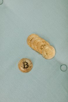 Close-up of gold bitcoin coins placed on a textured green fabric showcasing financial digital currency.