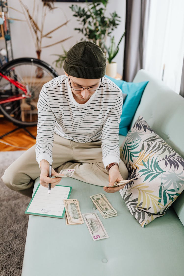 Man In Sitting On Green Couch Counting His Money 