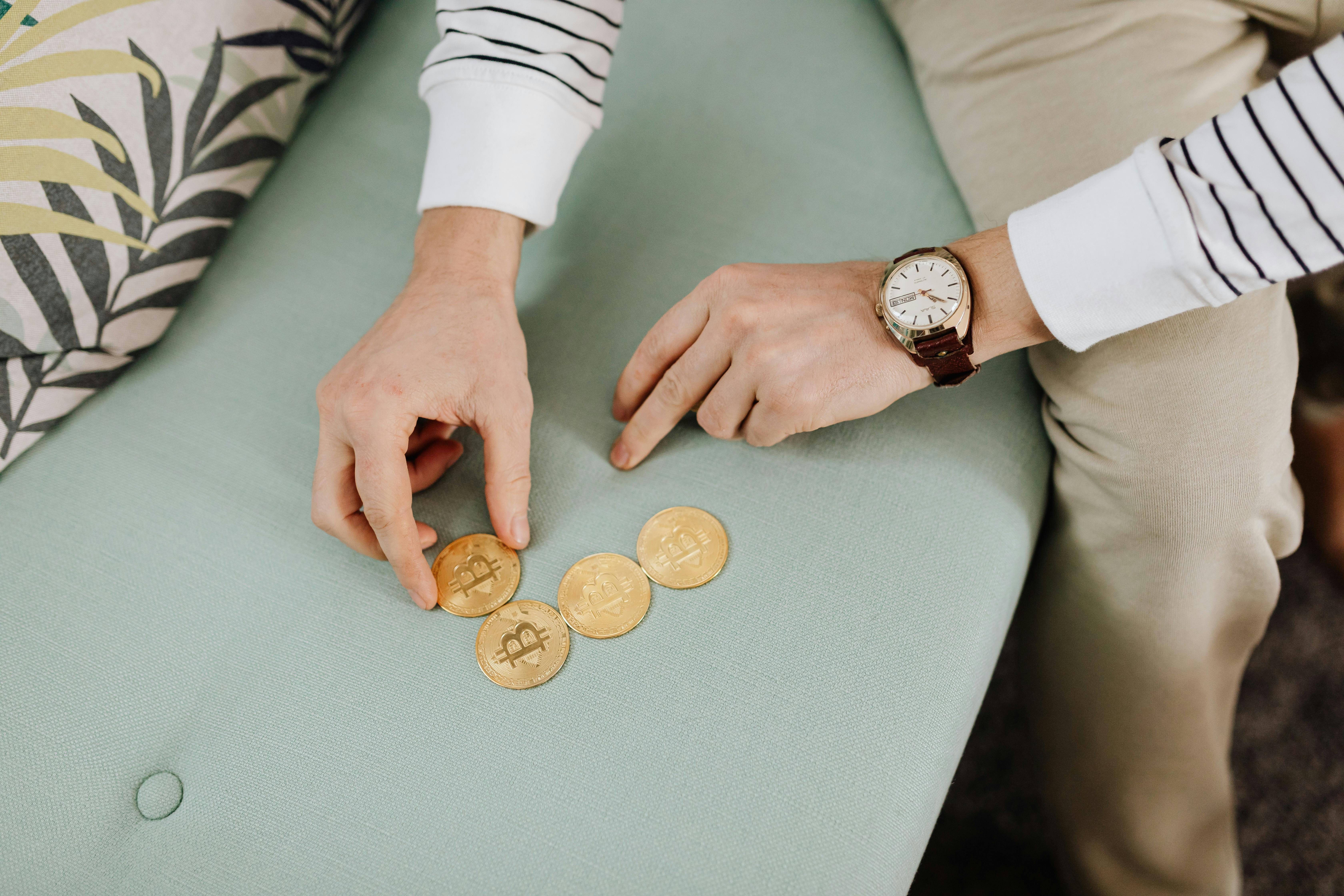 person wearing leather wristwatch holding gold coins