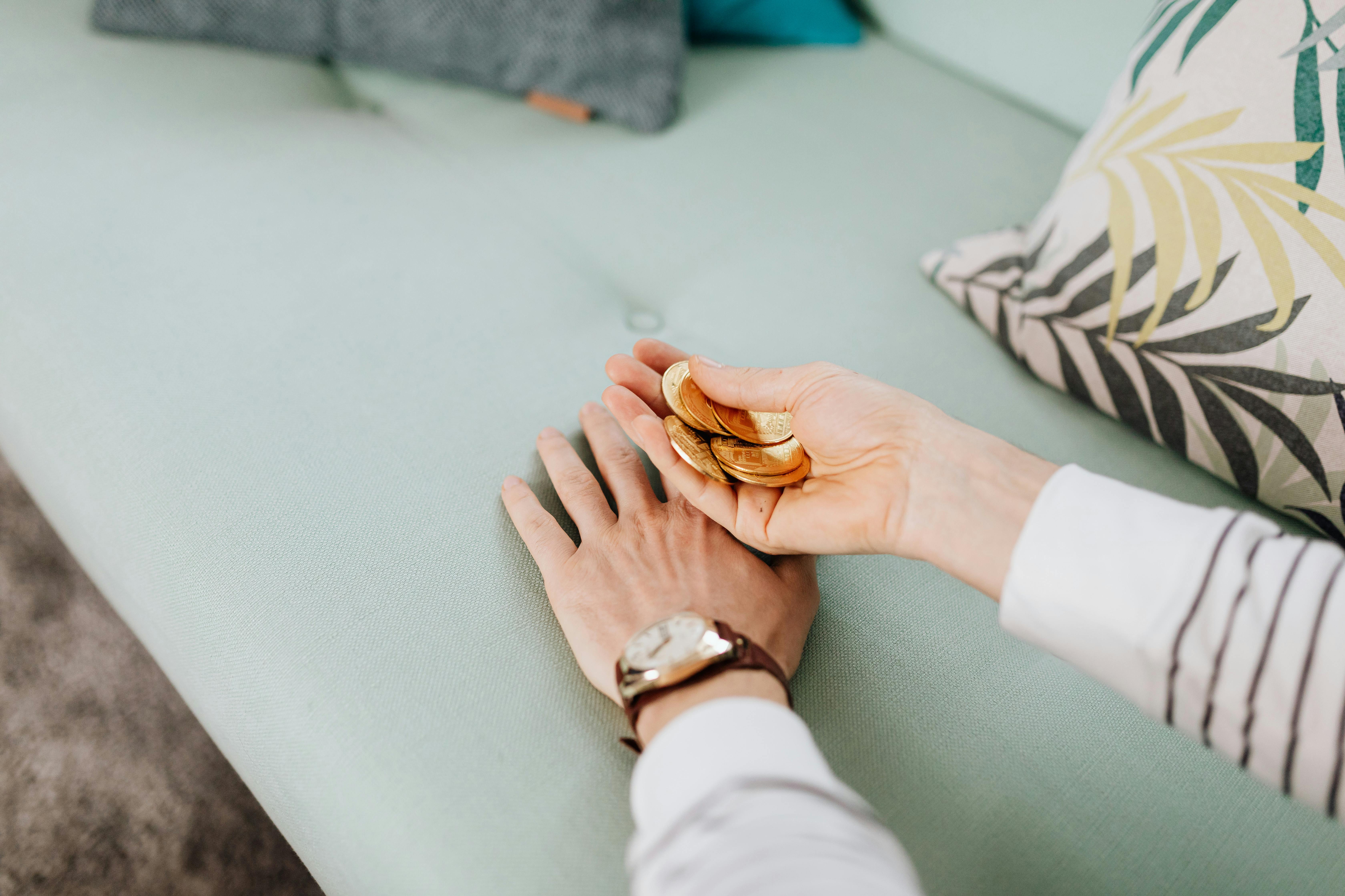 hand holding a bunch of gold coins