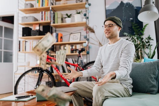 Smiling man in casual wear tossing money indoors, surrounded by bikes and books.