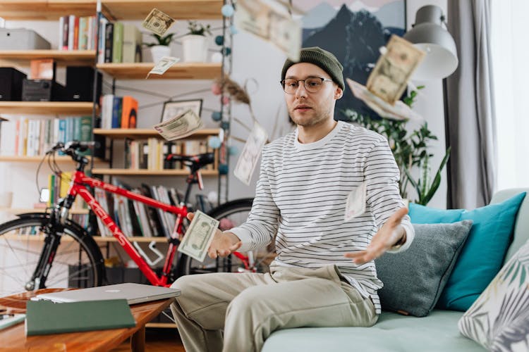 Man In Striped Long Sleeve Shirt Sitting And Throwing Money