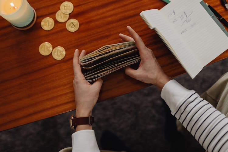 Person Counting Bills And Bitcoins On Table