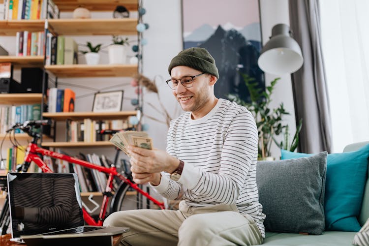 Man Sitting On Couch Holding Money