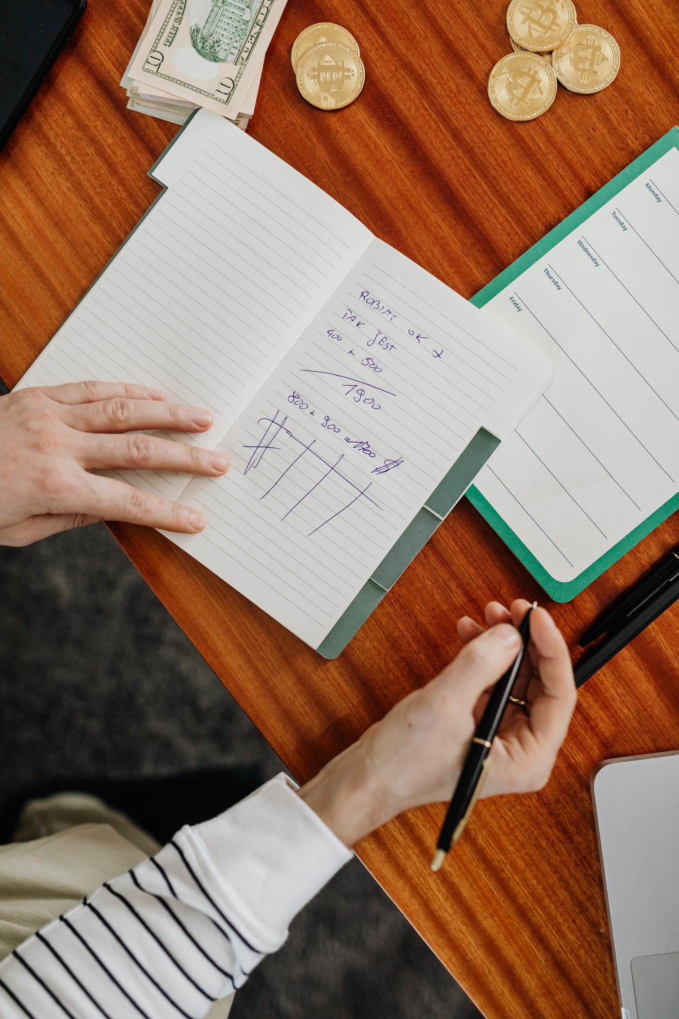 Hands writing financial calculations in a notebook