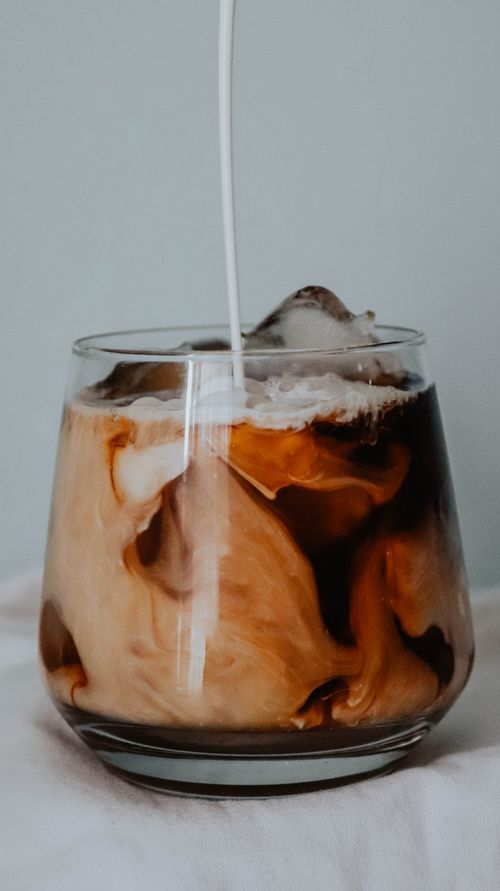 Free Close-up of iced coffee with cream swirling, capturing the rich blend in a glass. Stock Photo