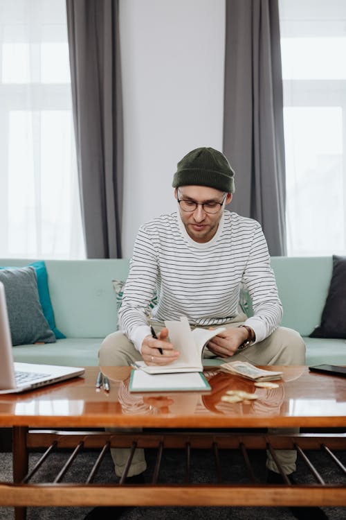 Free Man in Black and White Striped Long Sleeve Shirt Holding a Pen and Notebook Stock Photo