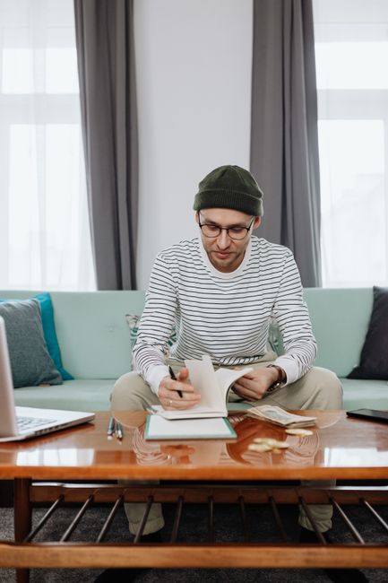 Adult male planning finances at a home desk with laptop and notebook. Adult male planning finances at a home desk with laptop and notebook.