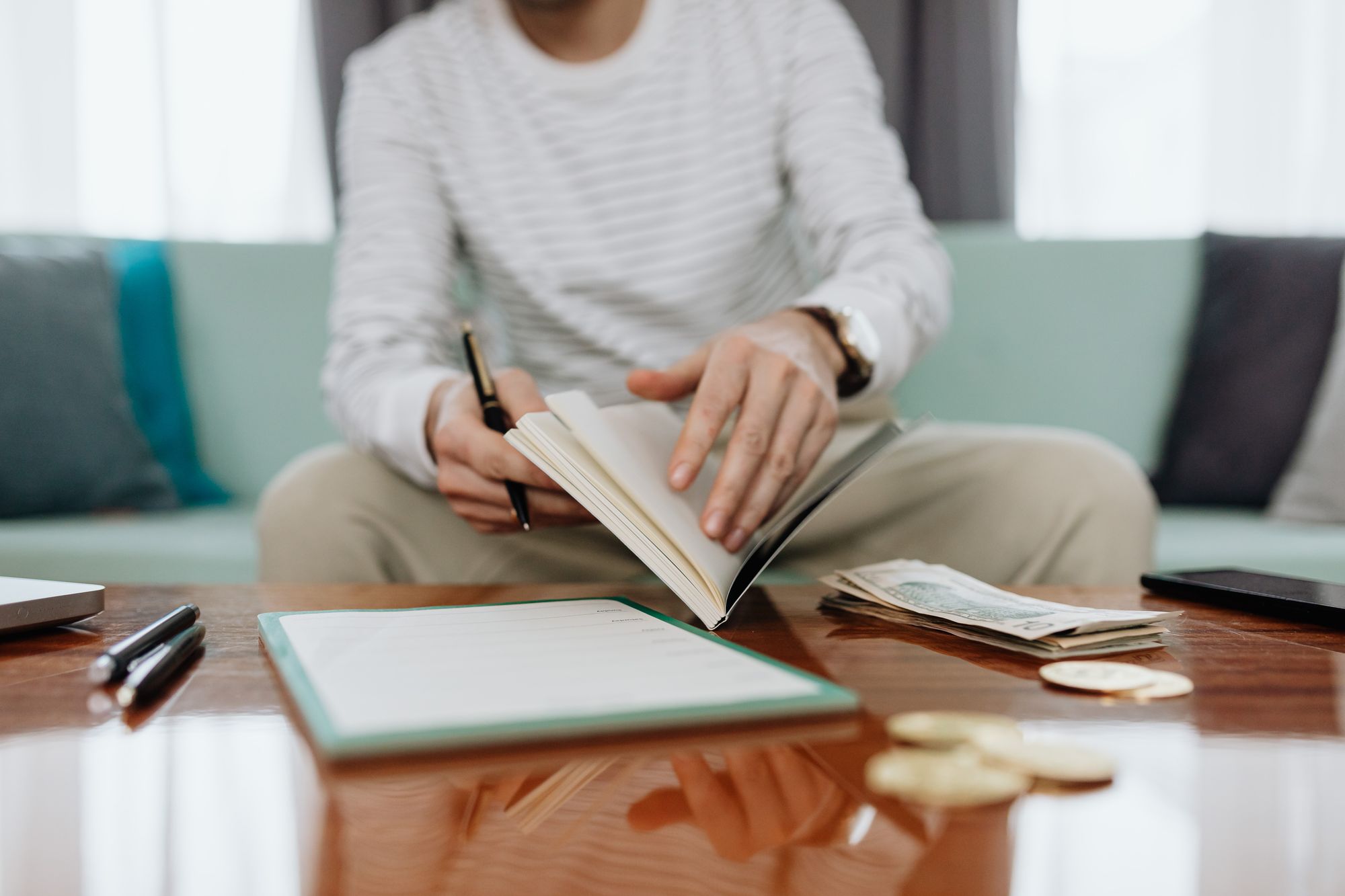 Person reviewing finances with a notebook, cash and laptop