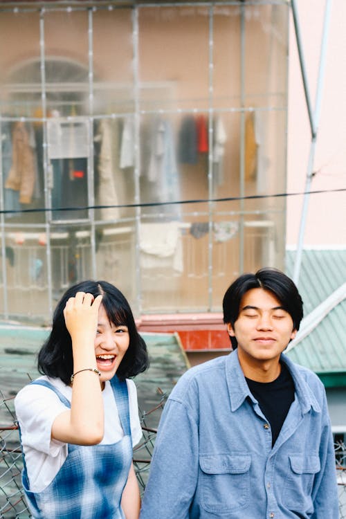 Young ethnic couple in casual clothes holding hands while standing on street and smiling
