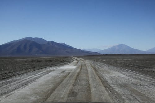 Gray Dirt Road Near Mountains Under Blue Sky