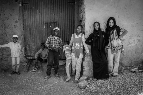Free Black and white photo of African children standing outside a rustic building, showcasing diversity and friendship. Stock Photo